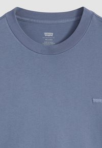 Afslappet-fit blå T-shirt lavet af bomuld, med en ribbet rund hals og et lille broderet logo i nederste højre hjørne.