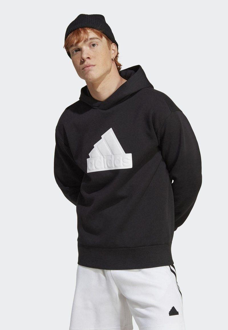 Black hoodie with a large white three-stripe logo on the front. Features a drawstring hood and ribbed cuffs. Worn with white shorts.