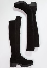 Botas negras de ante hasta la rodilla con suela gruesa, cierre con cremallera lateral, textura suave y costuras reforzadas a lo largo de las juntas.