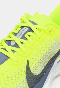 Nike Pegasus running shoe featuring a bright yellow upper with grey accents, textured mesh design, flat laces, and a cushioned sole.