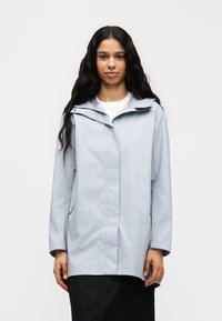 Svetlomodrá nepremokavá bunda s kapucňou, so zipsom vpredu, bočnými vreckami a voľným strihom. Hladká textúra a minimalistické dizajnové prvky.