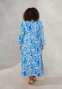 Blue maxi dress featuring a white paisley pattern, long sleeves, and a relaxed fit. The fabric has a smooth texture and a flowing design.