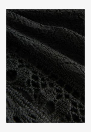 Black fabric with intricate lace patterns and textured embroidery, showing detailed stitching and raised floral designs.