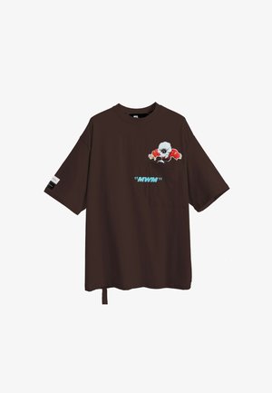 Camiseta marrón de gran tamaño con mangas cortas, que presenta un gráfico de personaje en el bolsillo del pecho y el texto "MWM" en azul.