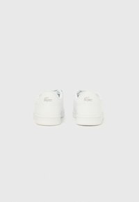 Άσπρα αθλητικά παπούτσια με λείο συνθετικό υλικό, στρογγυλή μύτη, σχέδιο χαμηλής κορυφής, υφή στις σόλες και μικρό ασημένιο λογότυπο.