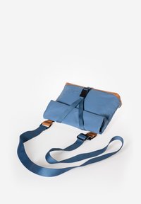 Borsa di stoffa blu con dettagli in pelle marrone, dotata di un design pieghevole, tracolla regolabile e una fibbia centrale per una chiusura sicura.