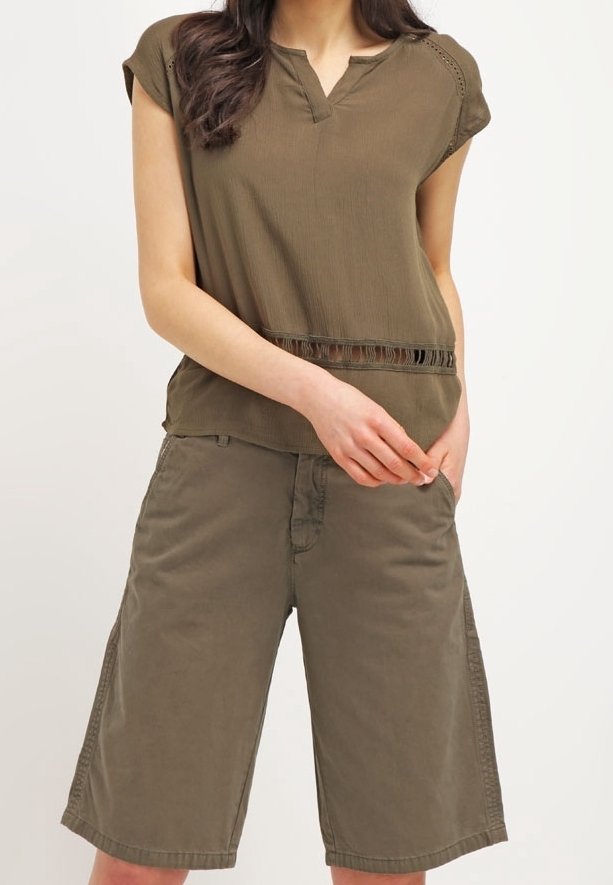 Top de manga corta color verde oliva con dobladillo partido y detalles sutiles, combinado con pantalones cortos a la altura de la rodilla en una tela ligera.