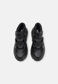 Svarta hög-toppsneakers tillverkade av slät syntetiskt material. Har elastiska remmar, vadderad krage och en kraftig sula.