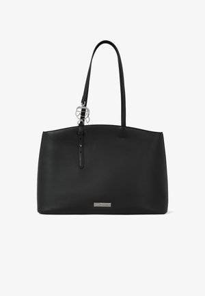 Fekete bőr táska két vállpánttal, ezüstszínű logófelirattal és díszítő medállal a pánton.