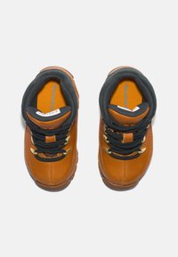 Zapatos de senderismo de cuero marrón con cordones negros y ojales dorados, que cuentan con cuellos acolchados y una suela de goma texturizada.