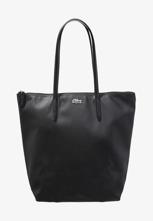 Sac cabas noir texturé avec deux longues anses, fermeture éclair sur le dessus et petit logo crocodile vert et rouge au centre devant.