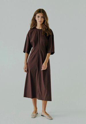 Brun, knælængde kjole med korte ærmer, en rund halsudskæring og en lige silhuet. Bæres med beige vævede slip-on sko.
