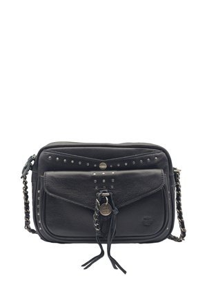 Sac de cuir noir porté en travers avec poche avant à rabat, clous en argent, bandoulière en chaîne et franges décoratives sur fond blanc.