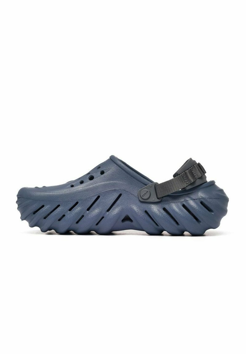 Zueco de goma azul con suela con relieve en zigzag, agujeros de ventilación y correa trasera ajustable. Diseño ligero para mayor comodidad y facilidad de uso.