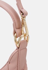 Blush leather handbag strap featuring gold-tone hardware and a clasp with "Valentino" engraved. Smooth texture with subtle stitching details.