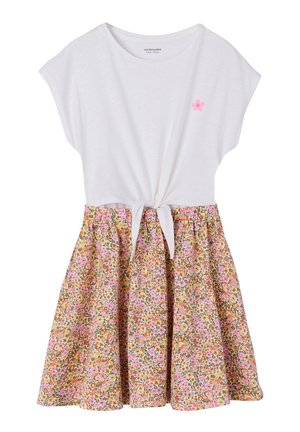 Weißes kurzärmeliges Oberteil mit Front-Schleife und kleinem pinkfarbenem Blumenmotiv, kombiniert mit einem hoch taillierten Blumenrock in Rosa-, Orange- und Grüntönen.