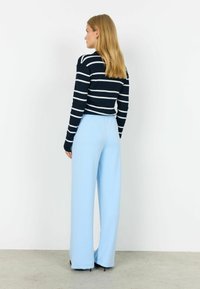 Námornícky modrý a biely pruhovaný rebrovaný sveter v kombinácii so svetlomodrými širokými nohavicami s elastickým pásom a mäkkou textúrou.