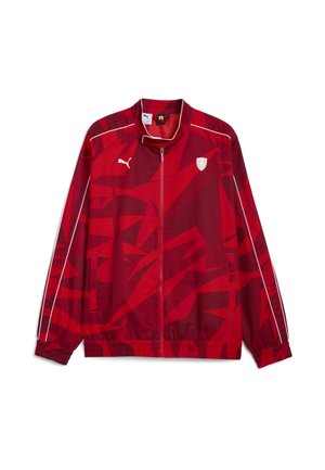 Rød Puma løbejakke med lynlås, hvid piping på ærmerne, abstrakt mønster og små hvide Puma- og Ferrari-logoer på brystet.