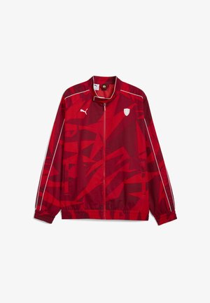 Rød Puma løbejakke med lynlås, hvid piping på ærmerne, abstrakt mønster og små hvide Puma- og Ferrari-logoer på brystet.