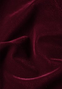 Tejido burdeos con una textura suave y lisa; ligeramente lustroso con sutiles variaciones en los patrones de tejido. Los pliegues crean suaves ondas.