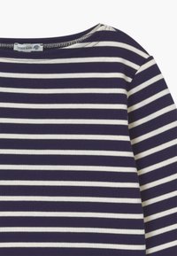 Koszula z długim rękawem w pionowe niebieską i białą w paski, wykonana z miękkiej bawełny, z okrągłym dekoltem i widocznymi detalami przeszycia.