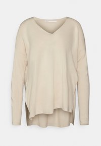 Maglione beige a maniche lunghe con scollo a V, vestibilità ampia, fessure laterali e texture morbida. Presenta un look a strati con un retro leggermente più lungo.