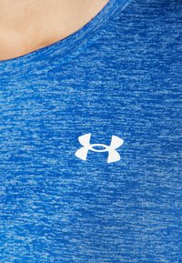 Camisa deportiva azul hecha de tela texturizada, con un logo blanco de Under Armour en el pecho y un cuello redondo.