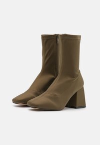Brązowe botki z tkaniny za kostkę, z ostro zakończonym noskiem, bocznym zamkiem błyskawicznym i masywnym kwadratowym obcasem. Wykończenie o fakturze z widocznymi przeszyciami.