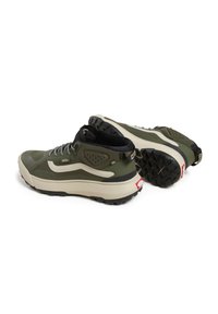 High-top hiking shoes in dark green and cream, featuring textured rubber soles, patterned laces, and Vans logo accents.