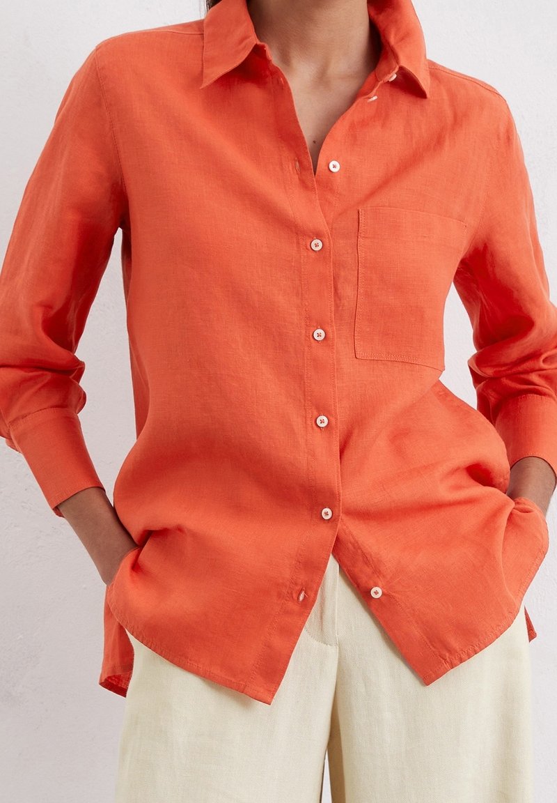Camicia button-up in lino arancione con colletto e taschino singolo sul petto. Maniche lunghe con polsini abbottonati e vestibilità rilassata.