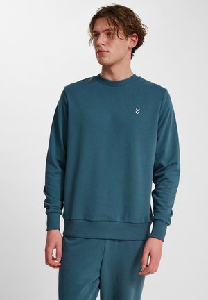 Teal sweatshirt gemaakt van zachte stof, met een ronde hals, geribbelde manchetten en een klein geborduurd chevronlogo op de borst.