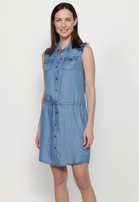Vestito camicia in denim, azzurro chiaro, design senza maniche, chiusura a bottoni, due tasche sul petto, vita regolabile con cordino, dettagli in pizzo sulle spalle.