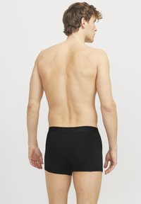 Schwarze Baumwoll-Boxershorts mit einem weichen elastischen Bund, die ein einfaches Design und eine glatte Textur aufweisen, von hinten gezeigt.
