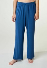 Blauwe, zachte loungebroek van stof met een wijd beenontwerp. Heeft een gegolfde elastische tailleband en kantafwerking aan de onderrand.