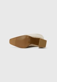 Beiger High-Heels mit Blockabsatz, strukturiertem, tanfarbenem Gummioberteil und glattem Obermaterial. Das Design ist schlank und minimalistisch gehalten.