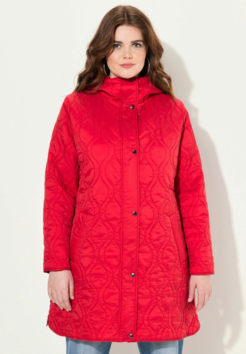 Red quilted long coat with a high collar, snap button closure, and textured wavy pattern. Features side pockets and a relaxed fit.