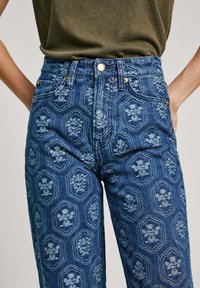 Džíny z modrej denimu s vysokým pásom, zdobené kvetinovým medailónovým vzorom, zlatými gombíkovými akcentmi a tradičným dizajnom s piatimi vreckami.