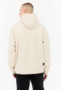 Crème-kleurige hoodie met een relaxed fit, drawstring capuchon en geribbelde manchetten. Voorzien van een klein logo-op-patch op de onderste zoom.