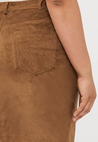 Brun semsket nederdel med en baglomme og en glat tekstur. Stoffet har en subtil glans, med præcise sømme langs kanterne.