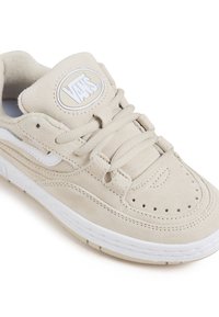 Sneaker in suede beige con dettagli bianchi, fori decorativi e punta tonda. Presenta un collare imbottito e lacci piatti. Logo sulla linguetta.