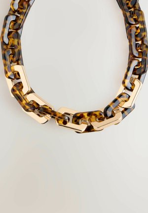 Klar akryl kedja halsband i sköldpaddsmönster med guldfärgad hårdvara. Har chunky länkar och slät textur.