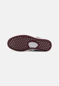 Vans footwear with a brown rubber outsole featuring a herringbone pattern, white accents, and a logo embossed on the heel.