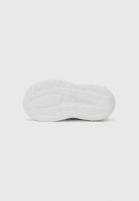 Semelle de chaussure blanche avec des motifs de grip texturés et un design incurvé. Comprend du caoutchouc flexible et une sensation lisse et rembourrée.