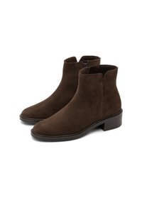 Une paire de bottines en daim marron foncé avec des petits talons carrés et des fermetures éclair sur le côté, présentée sur un fond blanc.