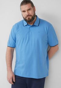 Lichtblauw poloshirt met een twee-knopen sluiting, contrasterende donkere kraagafwerking, korte mouwen en geborduurd logo op de linkerkant van de borst.