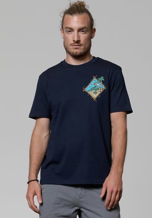 Navyblauw T-shirt met korte mouwen, gemaakt van katoen, met een kleurrafische afbeelding van palmbomen en een strand in een diamanten kader op de borst.