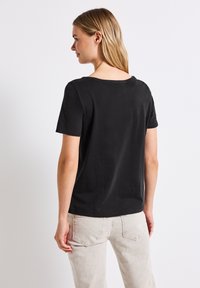 Svart t-shirt med kort ärm och rundad halsringning, tillverkad av mjukt bomullstyg. Enkelt design utan synliga mönster eller detaljer.