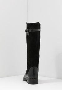 Černá vysoká kozačka sahající ke kolenu s semišovým svrškem, elegantním designem, nastavitelným páskem a hladkým koženým podpatkem.