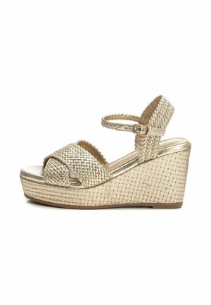 Sandalo platform in rafia dorata con design a fascia incrociata e cinturino alla caviglia. Presenta materiale testurizzato e una superficie liscia e lucida.