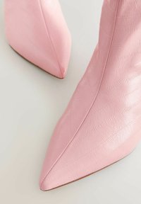 Zapatos de cuero rosas de punta con una superficie texturizada, que cuentan con costuras y un acabado suave. Los tacones son delgados y alargados.